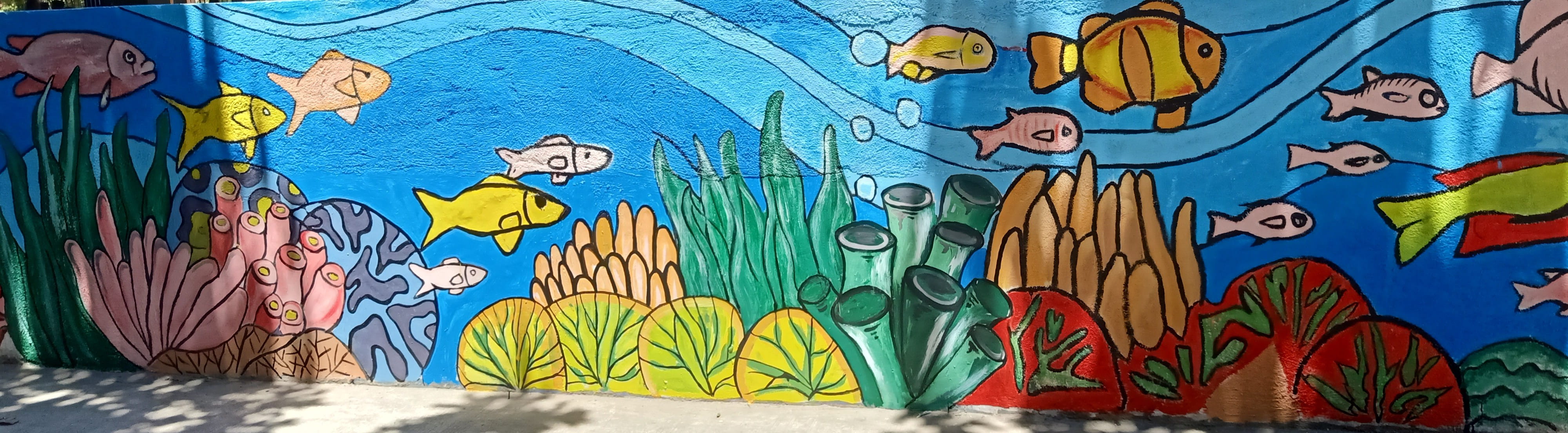 A wide panoramic view of a finished section of the mural showing diverse fish, sea plants, and tube sponges.